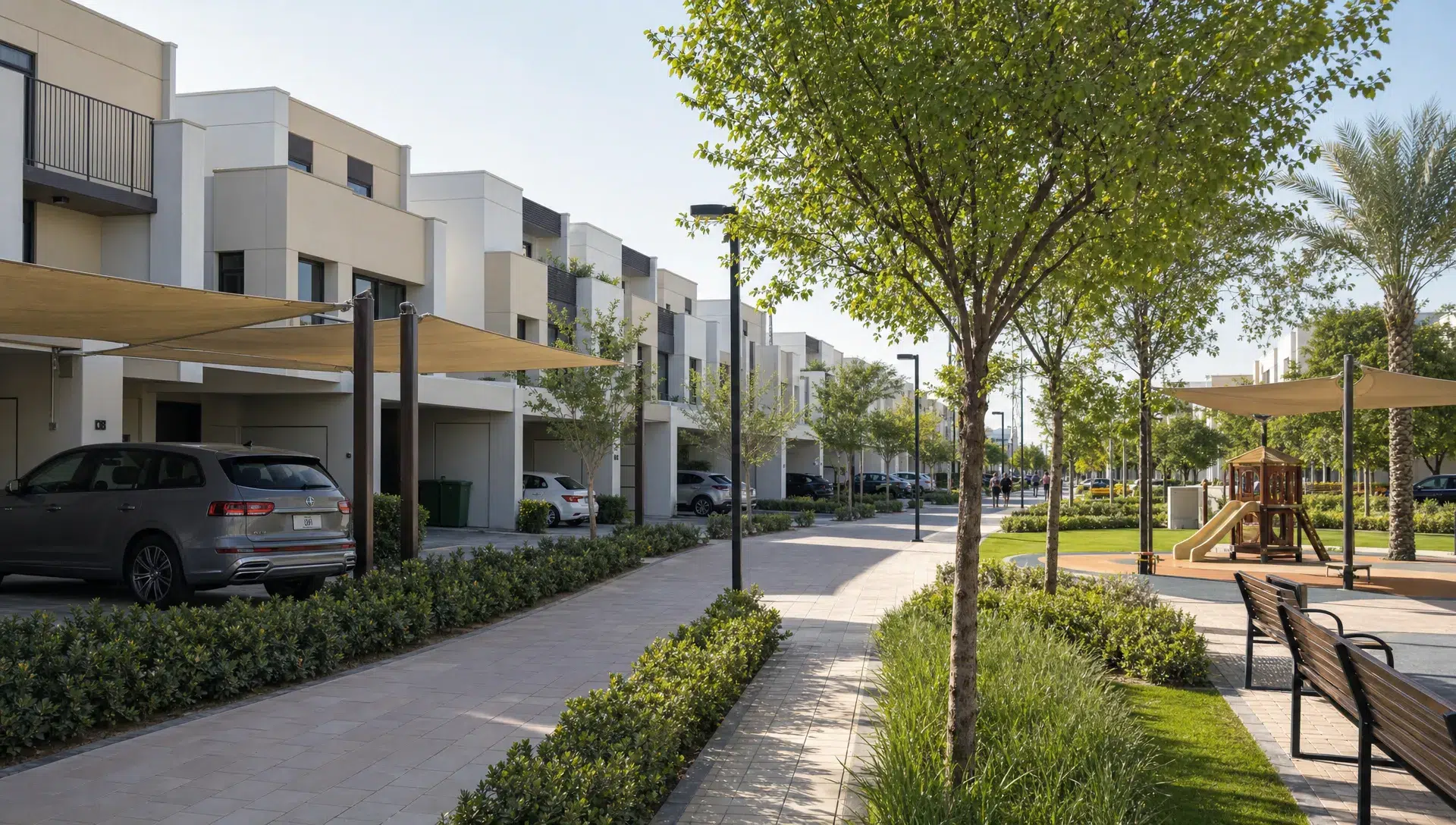 A Dubai townhouse community with rows of family homes, shaded walkways, parked cars, and a small park.